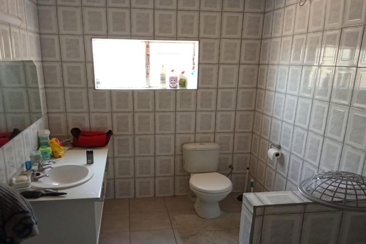 A functional bathroom featuring full-height wall tiling, a built-in vanity with a basin, and a standard toilet.