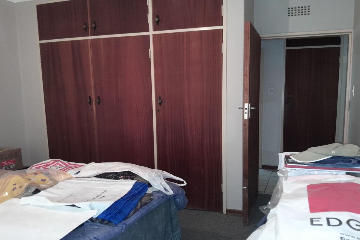 A bedroom featuring built-in wooden cupboards and a doorway leading to an adjacent room.