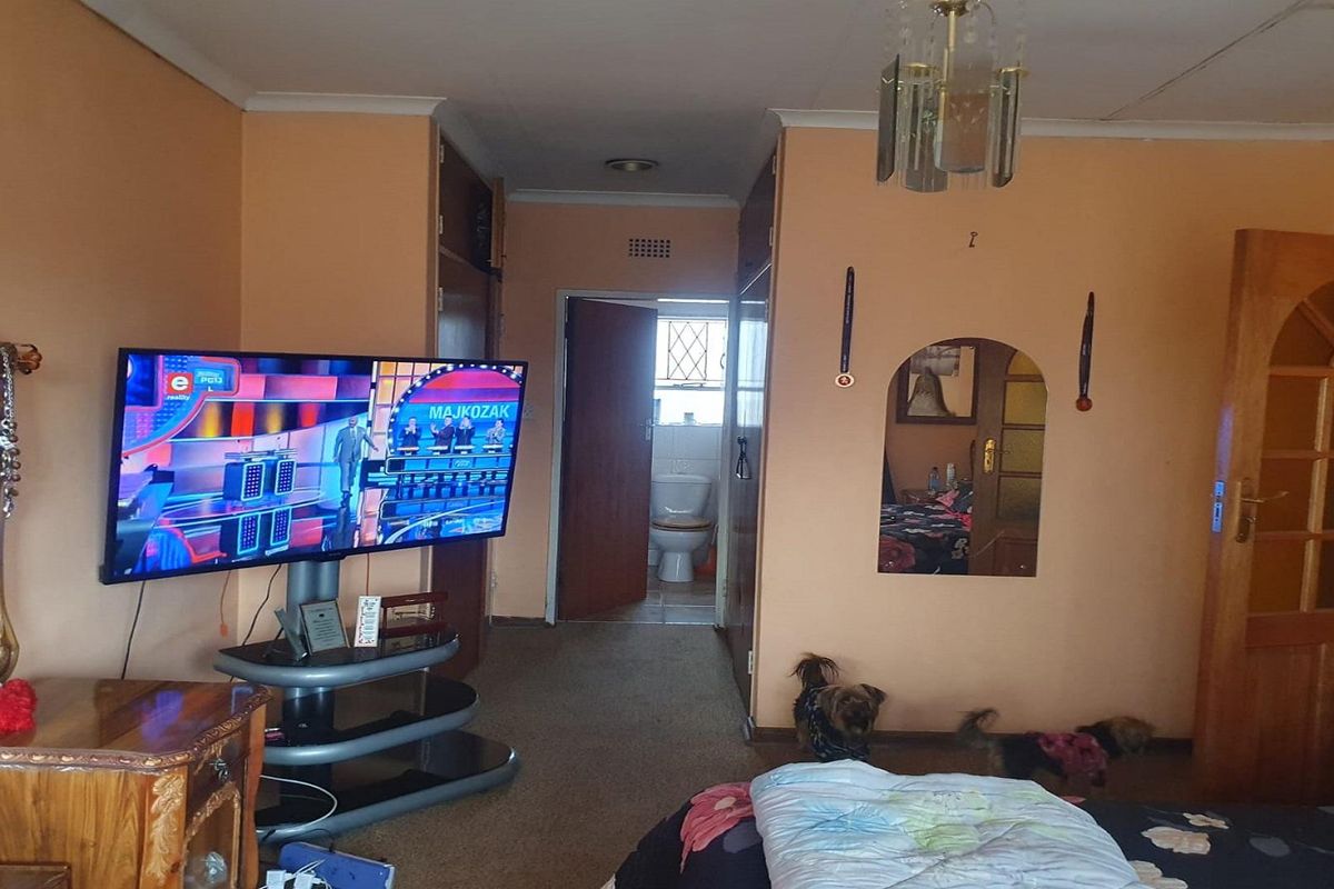 A bedroom featuring built-in cupboards, carpeted flooring, and an en-suite bathroom access point.