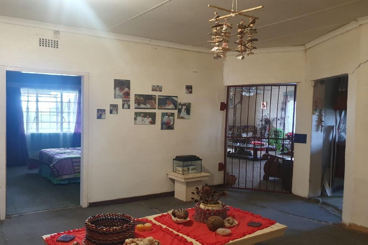 Interior view of a living area featuring tiled flooring, security gate access, and visible structural wall cracking.