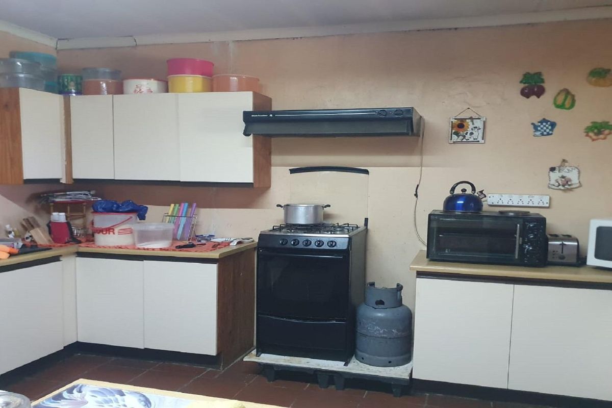 A functional kitchen area featuring built-in cabinetry, a freestanding stove with extractor fan, and tiled flooring.