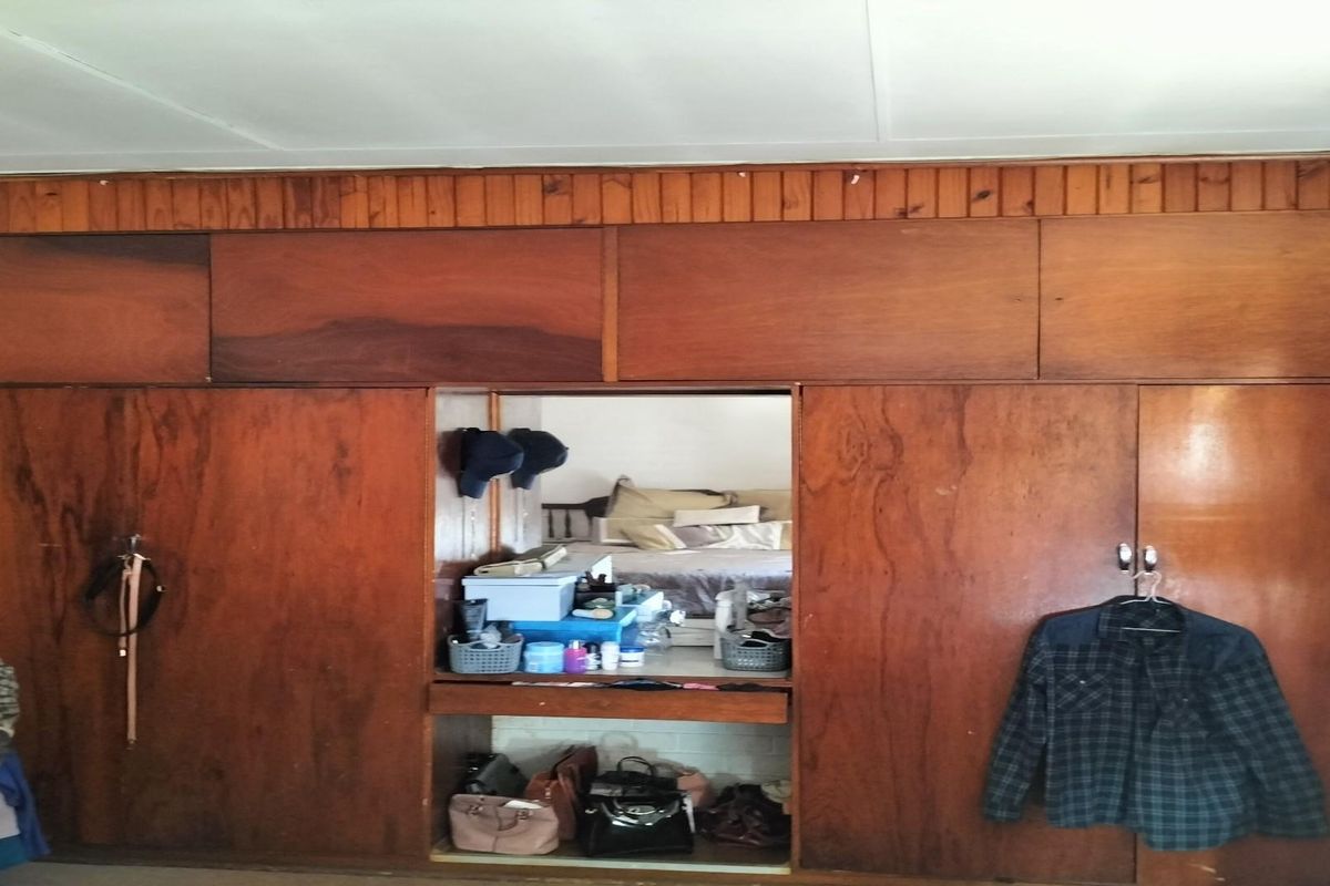 Bedroom featuring extensive floor-to-ceiling built-in wooden cabinetry with a central vanity or display niche.
