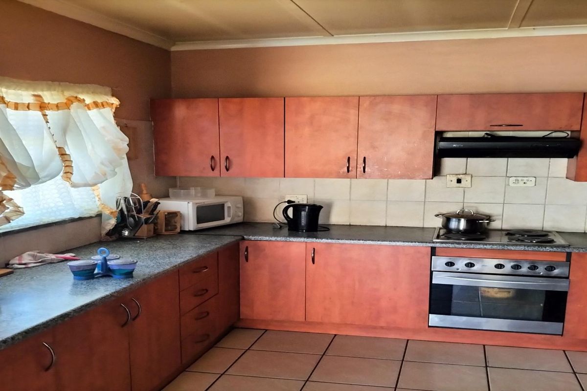 A functional kitchen featuring wood-look cabinetry, granite-style countertops, a built-in oven, and a stainless steel extractor fan.