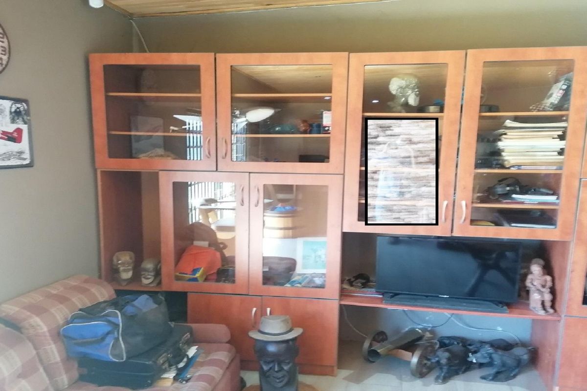 A living room featuring a large, built-in wooden wall unit with glass-fronted display cabinets and integrated shelving.