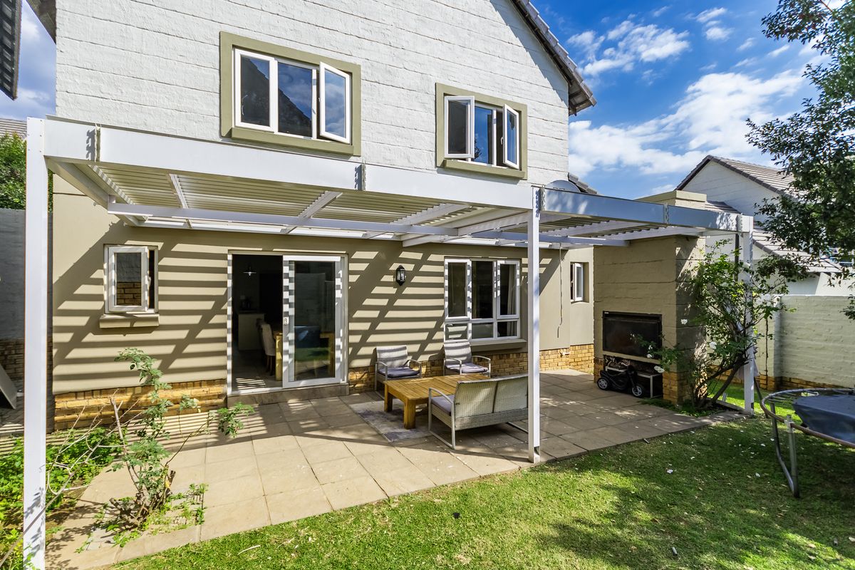 Rear view of the property featuring a paved patio area with a covered pergola structure and a built-in braai.