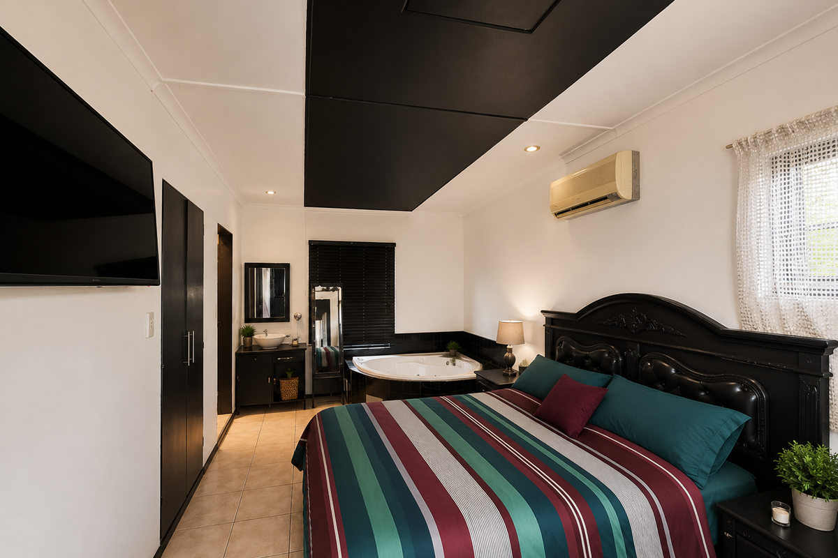 Spacious bedroom featuring an integrated corner spa bath, vanity basin, built-in cabinetry, and wall-mounted air conditioning unit.