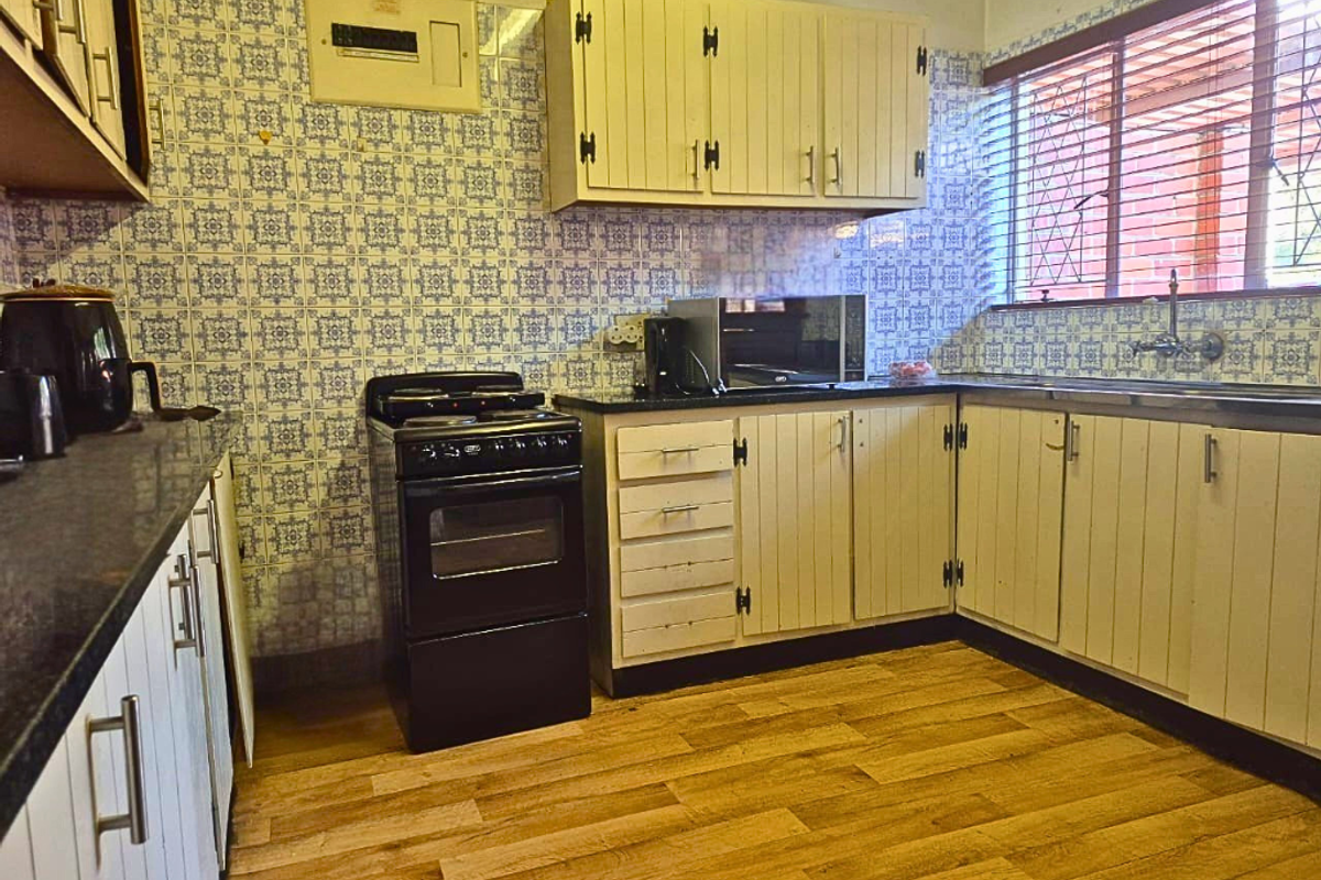 Functional kitchen featuring wood-look flooring, ample cabinetry, a freestanding stove, and a double sink with a window view.