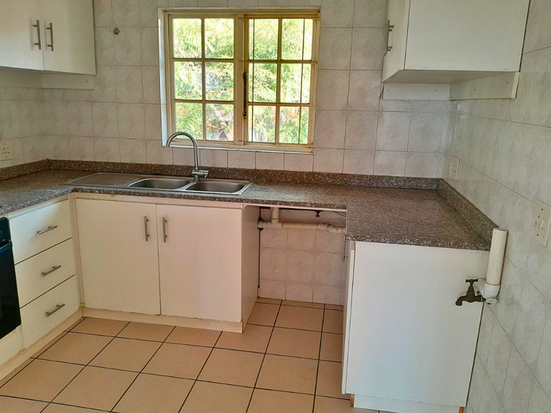 A functional kitchen featuring tiled splashbacks, laminate countertops, a double bowl sink, and built-in cabinetry with an integrated oven.