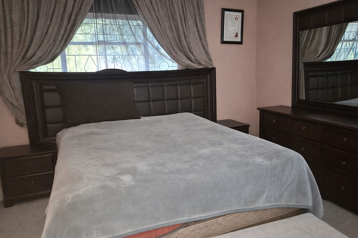 A bedroom featuring a window with security bars and neutral wall finishes.