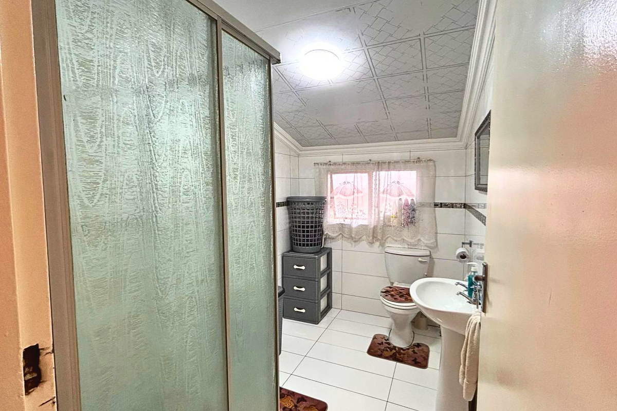 A functional bathroom featuring a pedestal sink, toilet, and a shower enclosure with textured glass doors.