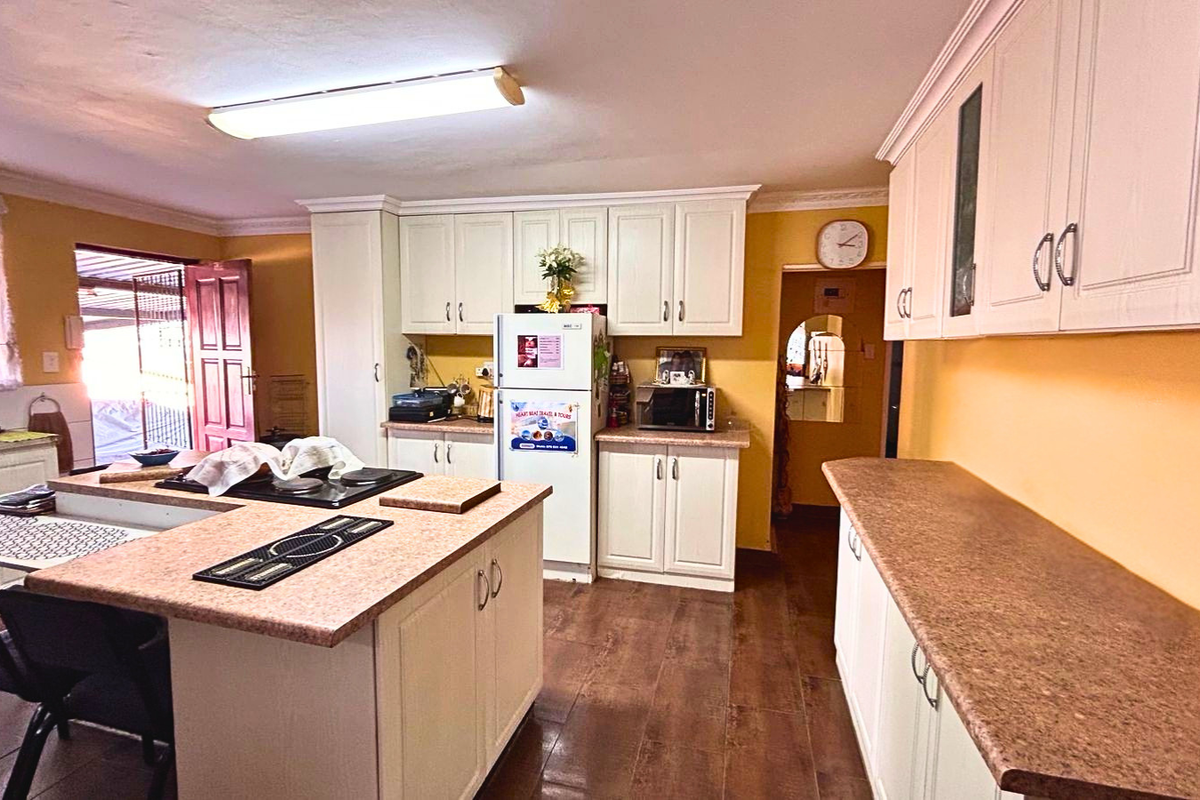 Spacious kitchen featuring white cabinetry, a central island with a built-in hob, and ample laminate countertop workspace.