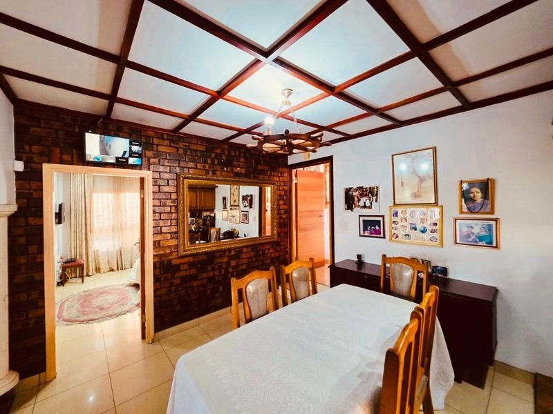 Dining room featuring an exposed brick feature wall, tiled flooring, and a distinctive coffered ceiling with a nautical-style chandelier.