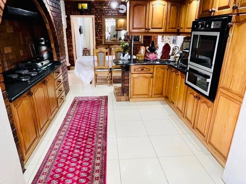 Traditional kitchen featuring extensive wooden cabinetry, granite countertops, a built-in double oven, gas hob, and a distinctive brick arch feature.