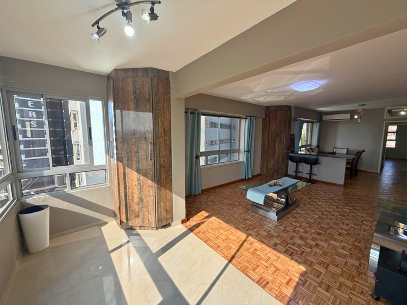 Spacious open-plan living and dining area featuring a mix of parquet and tiled flooring, built-in cabinetry, and a breakfast bar with integrated lighting.