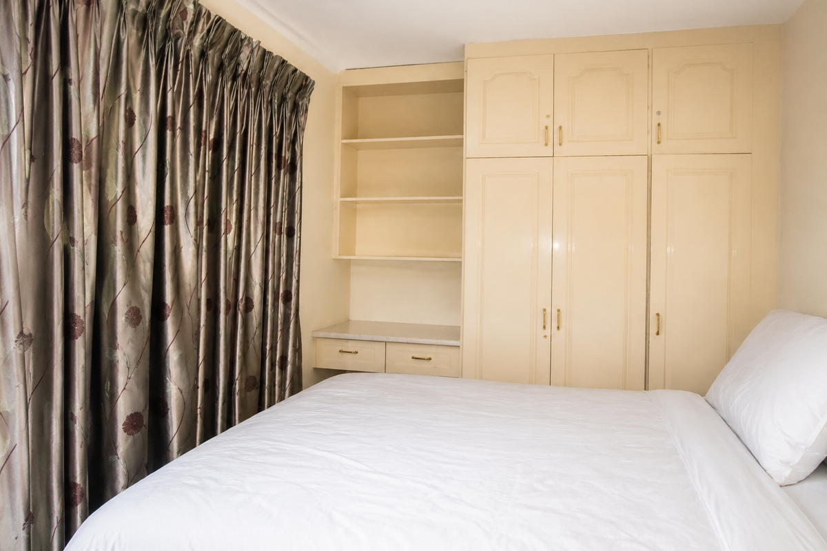 A bedroom featuring built-in cupboards with integrated shelving and recessed ceiling lighting.