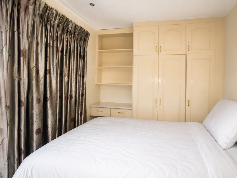 A bedroom featuring built-in cupboards with integrated shelving and recessed ceiling lighting.