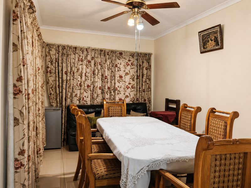 A functional dining room featuring tiled flooring, coved cornicing, and a central ceiling fan, providing a comfortable space for family meals.