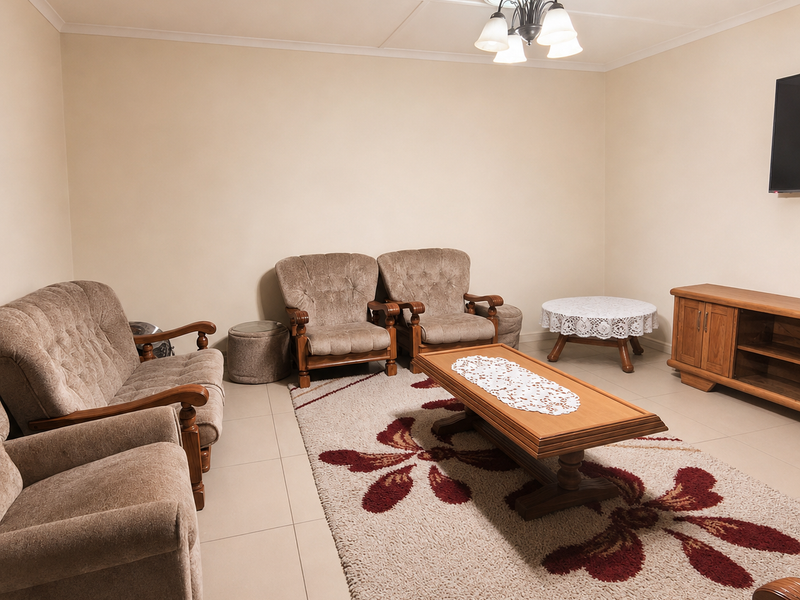 A spacious living room featuring neutral tiled flooring and a central ceiling light fixture, providing a functional and comfortable area for relaxation.