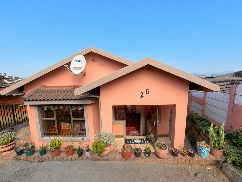 Front elevation of a single-story house featuring a peach-colored facade, tiled roof, and a secure entrance gate.