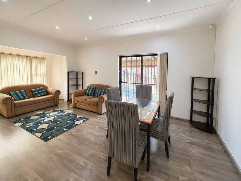 Open-plan living and dining area featuring modern laminate flooring, recessed downlighting, and a sliding glass door providing access to the exterior.