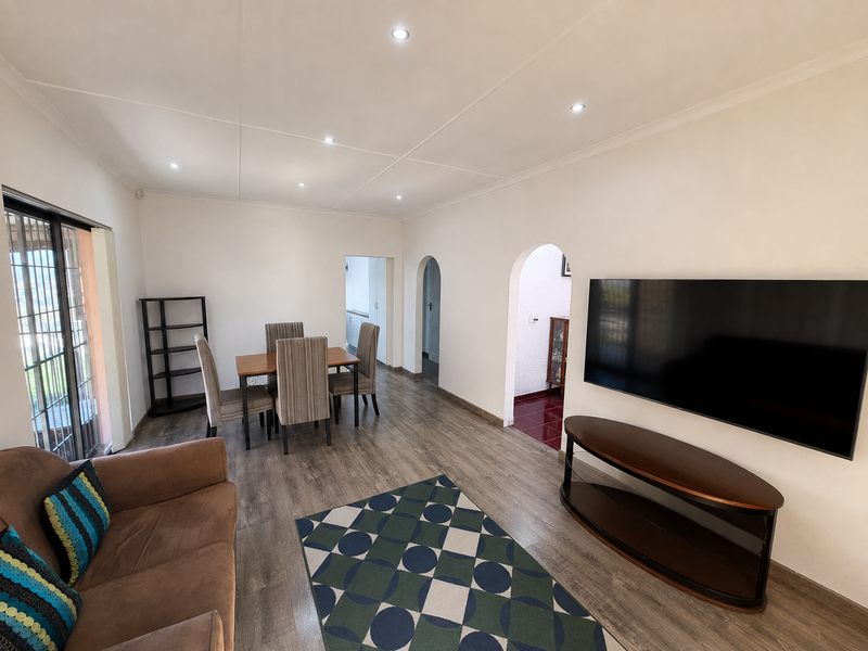 Open plan living and dining area featuring laminate flooring, recessed downlighting, and arched transitions to adjacent spaces.