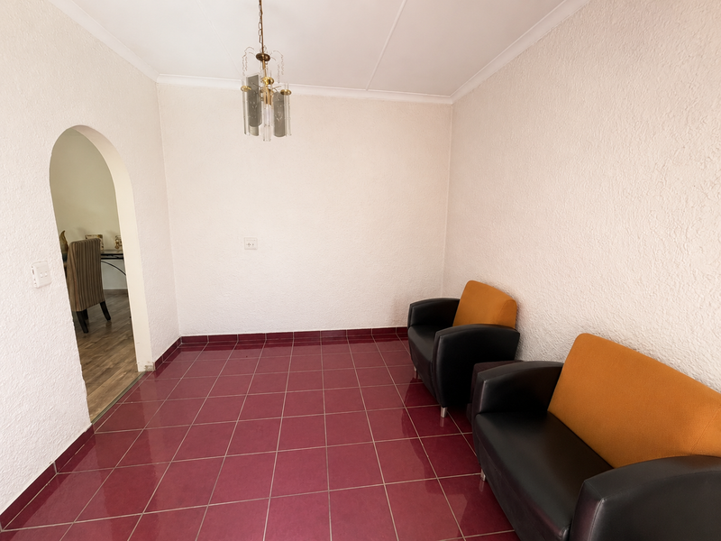 A living area featuring textured walls, ceramic tile flooring, and an arched doorway leading to an adjacent room.
