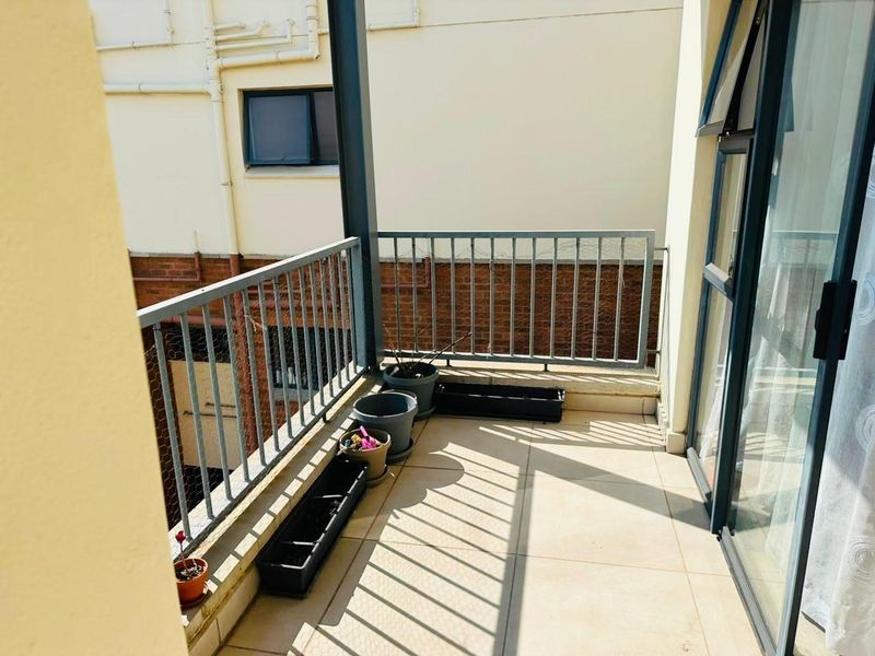 A private balcony featuring tiled flooring and a metal balustrade, accessible via a sliding glass door.