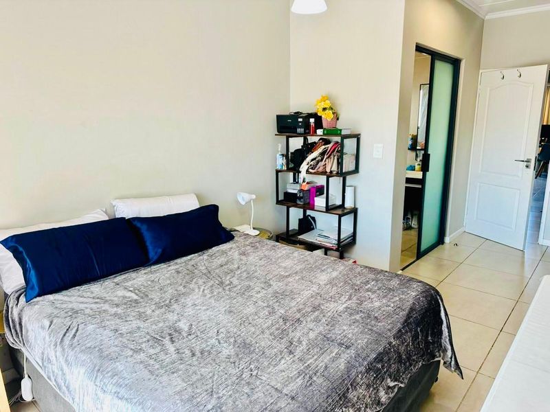A bedroom featuring tiled flooring, a frosted glass door leading to an en-suite, and a standard panel door.