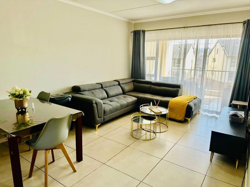 Open-plan living and dining area featuring neutral tiled flooring and a large sliding glass door providing access to the balcony.