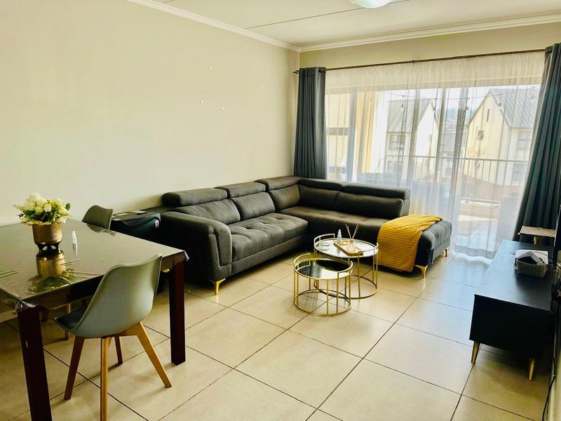 Open-plan living and dining area featuring neutral tiled flooring and a large sliding glass door providing access to the balcony.