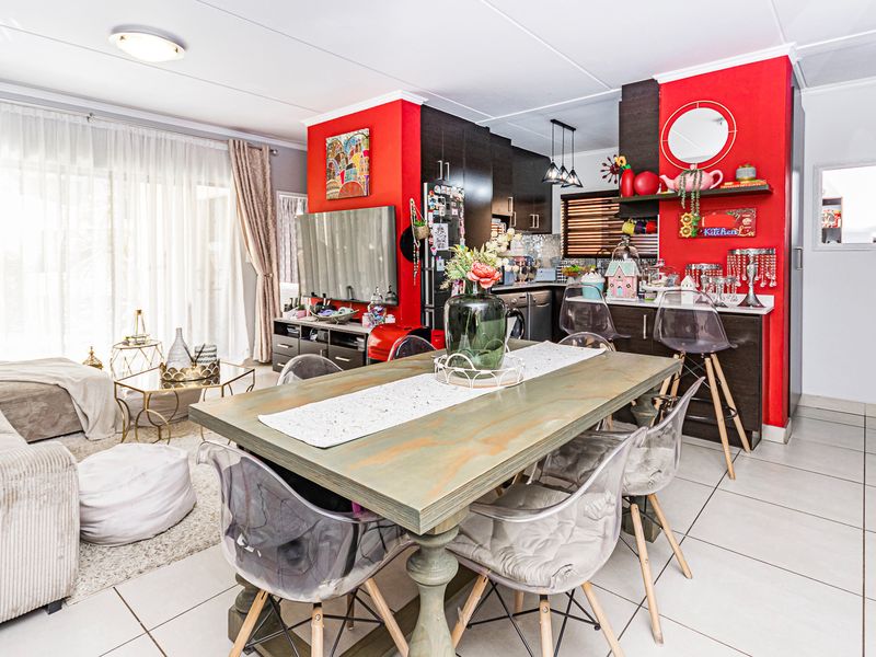 Open-plan living and dining area featuring tiled floors, a modern kitchen with breakfast bar, and direct access to an outdoor space through sliding doors.