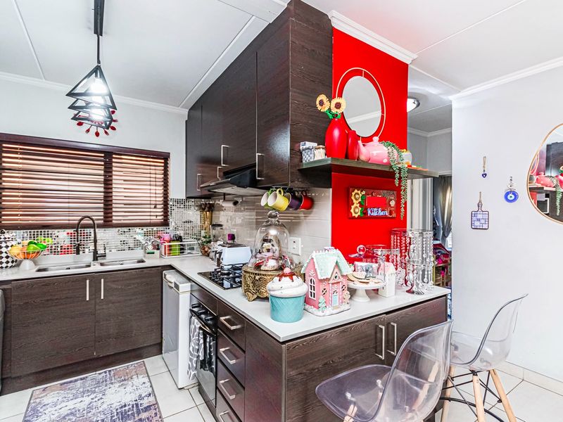 A functional kitchen featuring dark wood cabinetry, a gas hob, built-in oven, extractor fan, and a mosaic tile backsplash with a double sink.