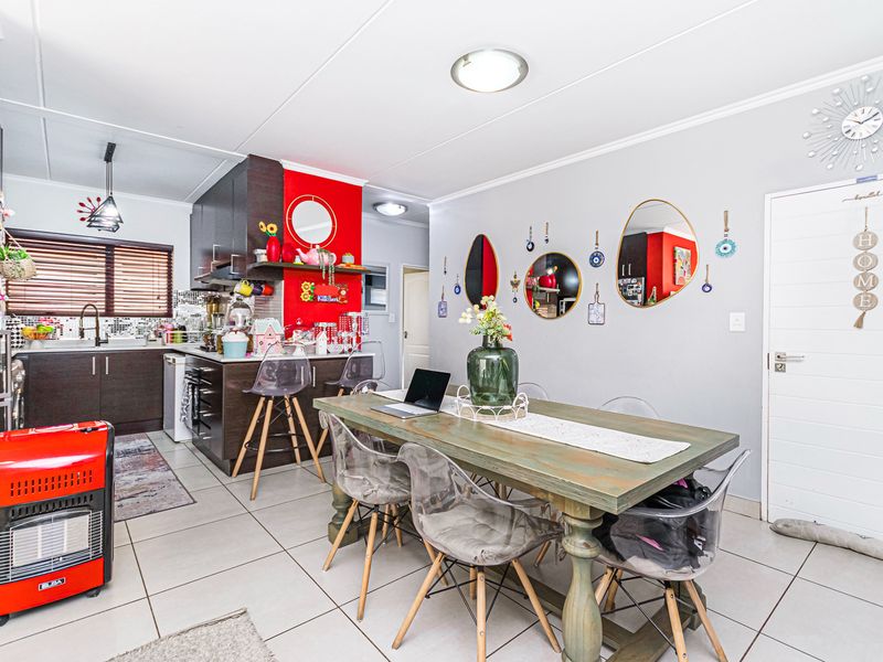 Open plan kitchen and dining area featuring tiled flooring, built-in cabinetry, and a breakfast bar, creating a functional living space.