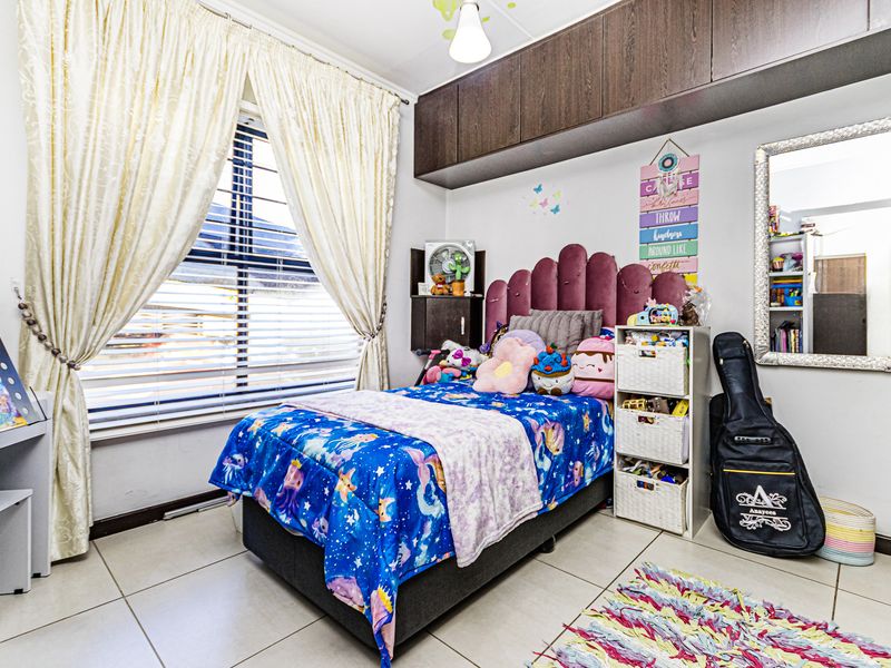 A bedroom featuring tiled flooring, venetian blinds, and built-in overhead storage cabinetry.