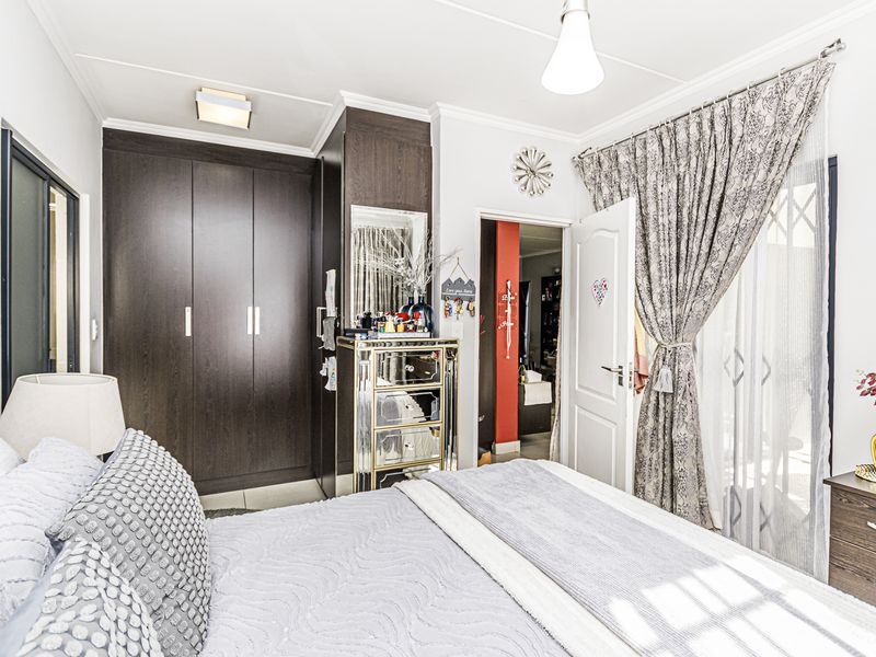 A well-maintained bedroom featuring dark wood built-in cupboards, neutral wall finishes, and direct access to an outdoor area through a sliding door.