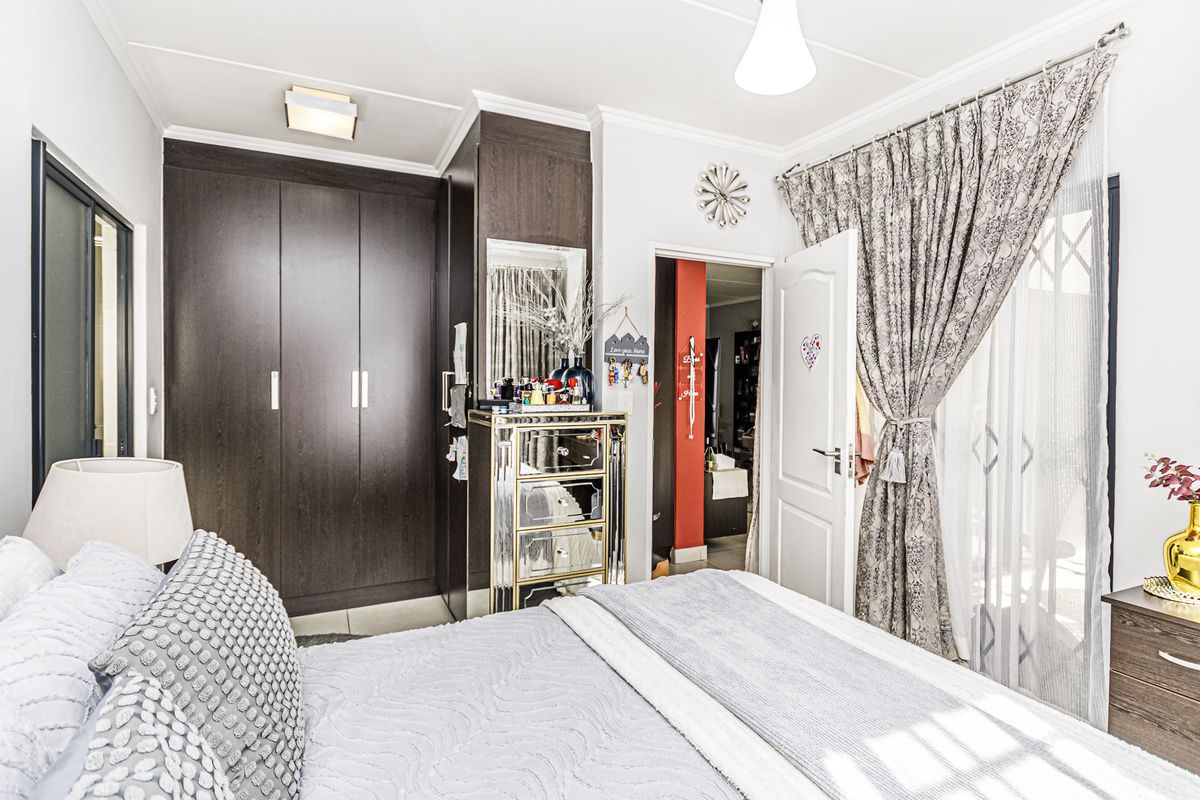 A well-maintained bedroom featuring dark wood built-in cupboards, neutral wall finishes, and direct access to an outdoor area through a sliding door.