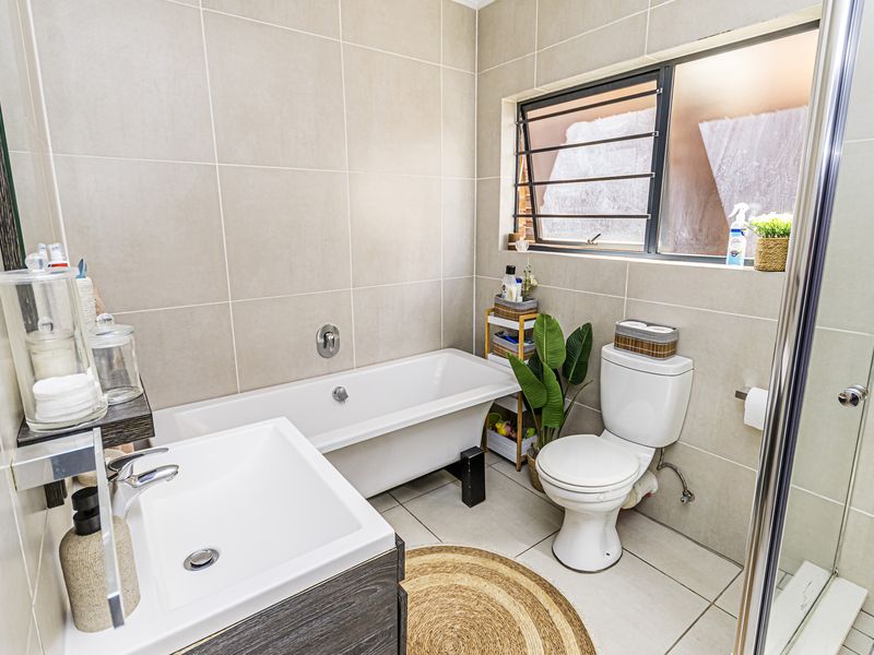 Modern bathroom featuring a bathtub, separate shower enclosure, vanity with basin, and neutral wall and floor tiling.