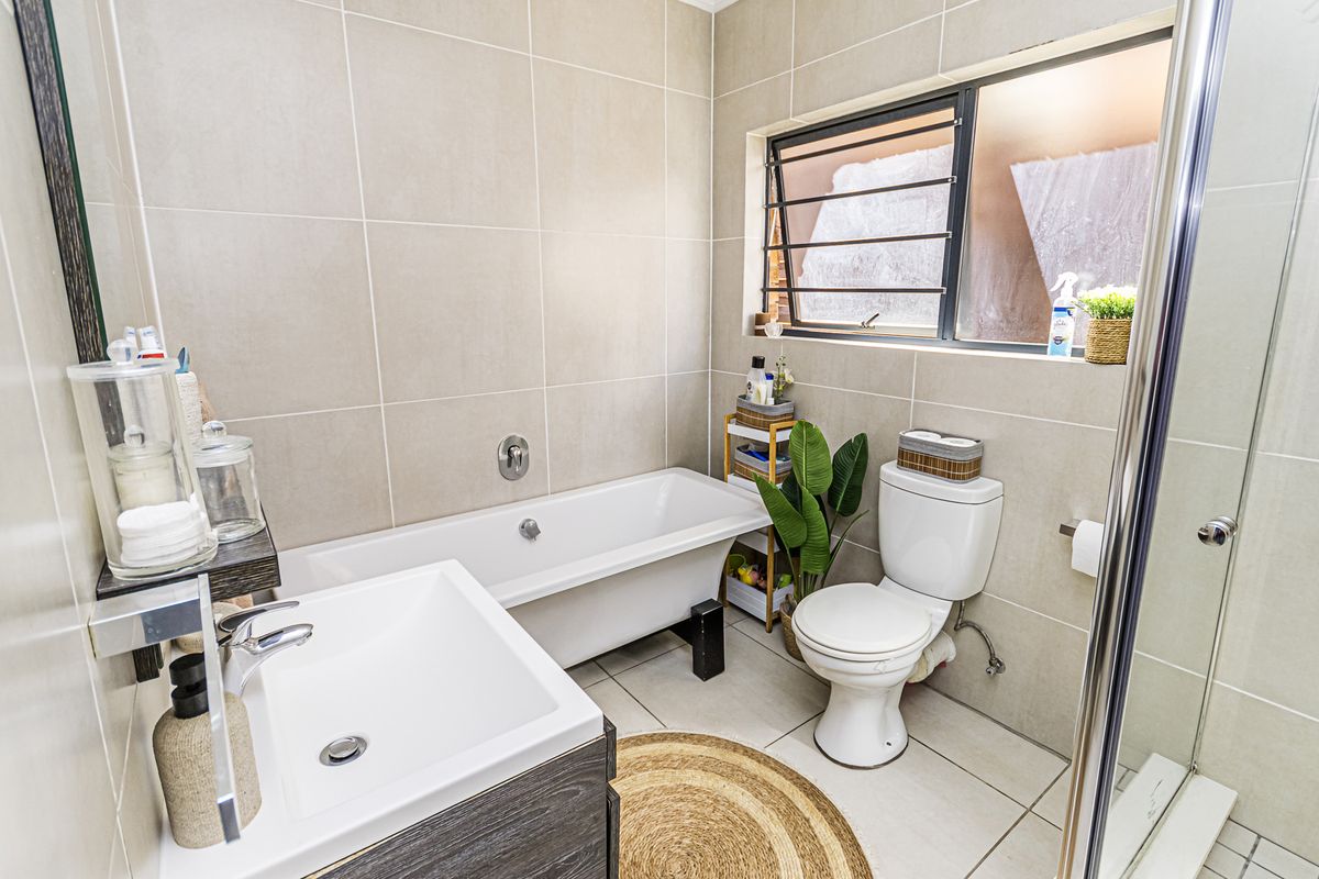 Modern bathroom featuring a bathtub, separate shower enclosure, vanity with basin, and neutral wall and floor tiling.