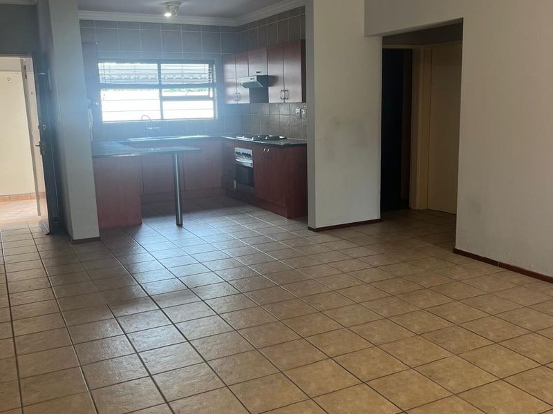 An open-plan living and kitchen area featuring tiled flooring, built-in cabinetry, and a breakfast counter, offering a functional and versatile layout.