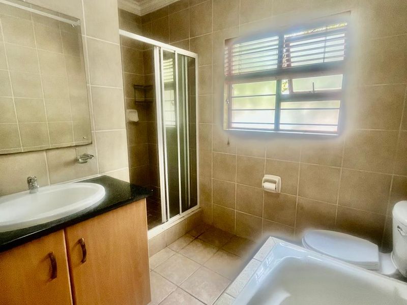 A functional bathroom featuring a vanity with basin, a separate shower enclosure, a bathtub, and neutral wall and floor tiling.