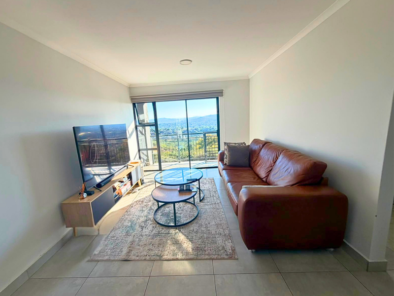 A bright living room featuring large sliding glass doors that provide natural light and access to a balcony with scenic views.
