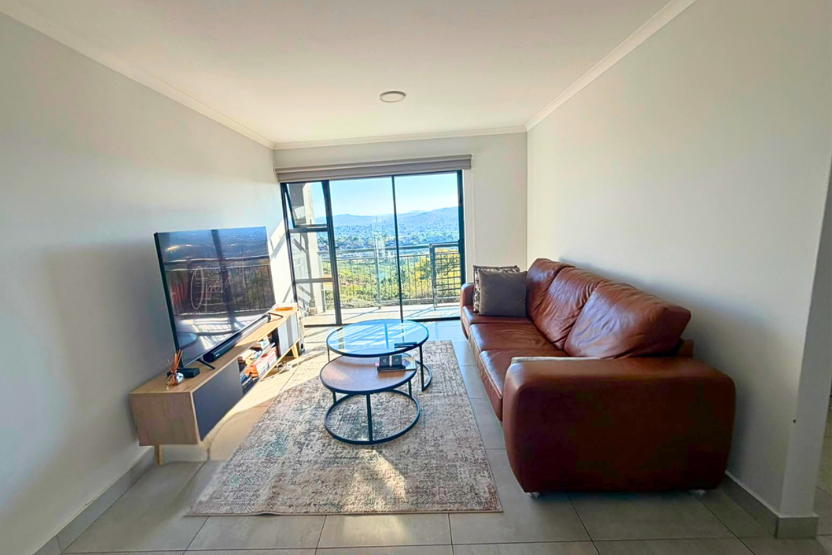 A bright living room featuring large sliding glass doors that provide natural light and access to a balcony with scenic views.