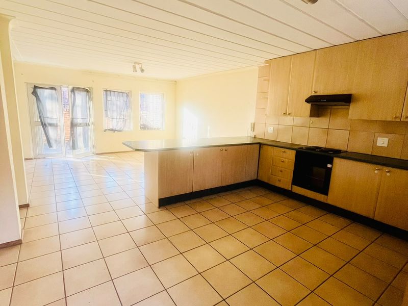 Spacious open-plan kitchen and living area featuring tiled flooring, built-in cabinetry, and direct access to the exterior through glass doors.