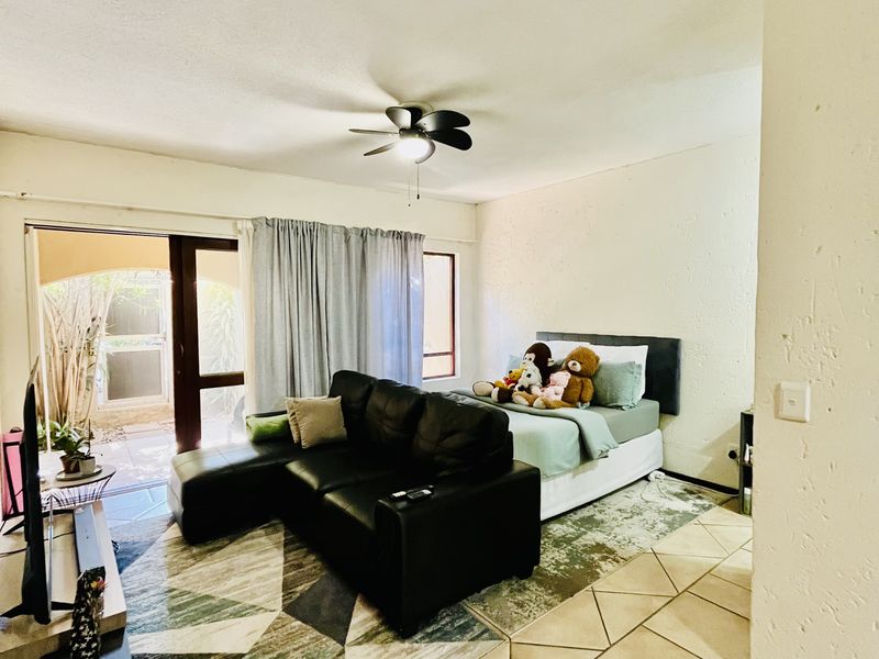 Open-plan living and bedroom area featuring tiled flooring, a ceiling fan, and direct access to an outdoor patio through a sliding glass door.