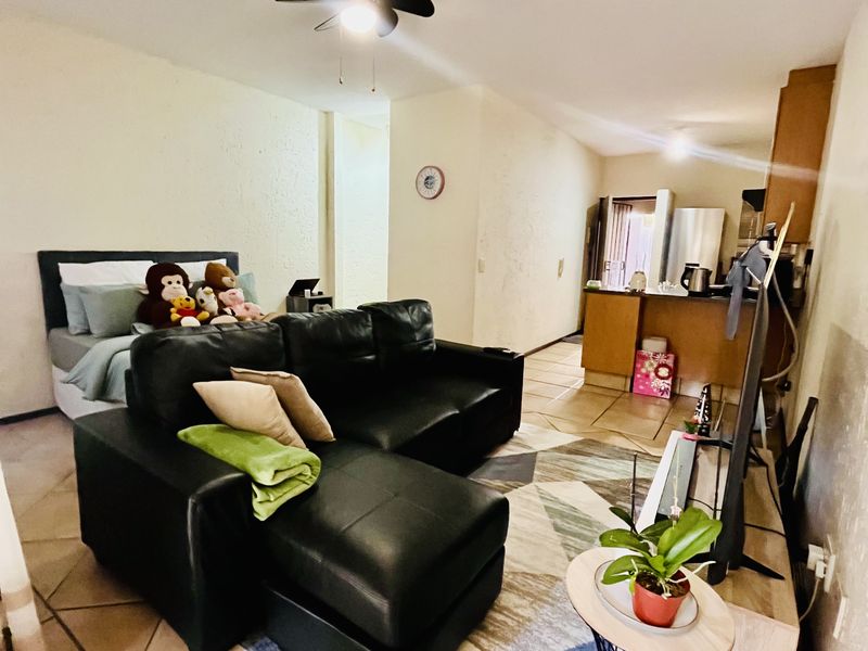 Open plan living area featuring tiled flooring, a ceiling fan, and an integrated kitchen space with cabinetry.
