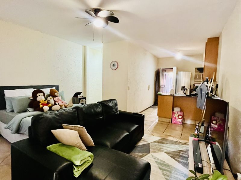 Open-plan living area featuring tiled flooring, a ceiling fan, and an integrated kitchen space with built-in cabinetry.