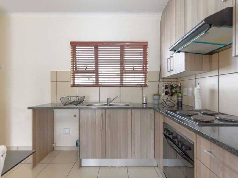 A functional kitchen featuring laminate cabinetry, granite countertops, a built-in oven with hob, and a tiled splashback.