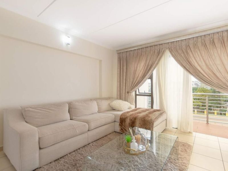 A bright living room featuring tiled flooring and a sliding glass door that provides direct access to a private balcony.