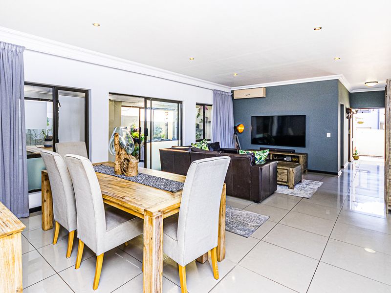 Spacious open-plan living and dining area featuring large format floor tiles, recessed lighting, and sliding glass doors providing access to the outdoor space.