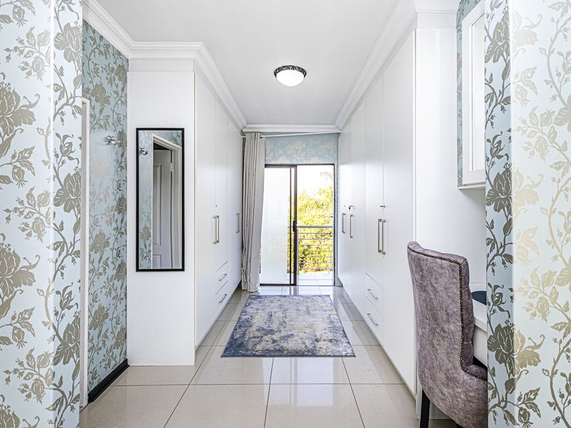 A well-maintained dressing room or bedroom featuring extensive built-in cabinetry, tiled flooring, and direct access to an outdoor balcony.
